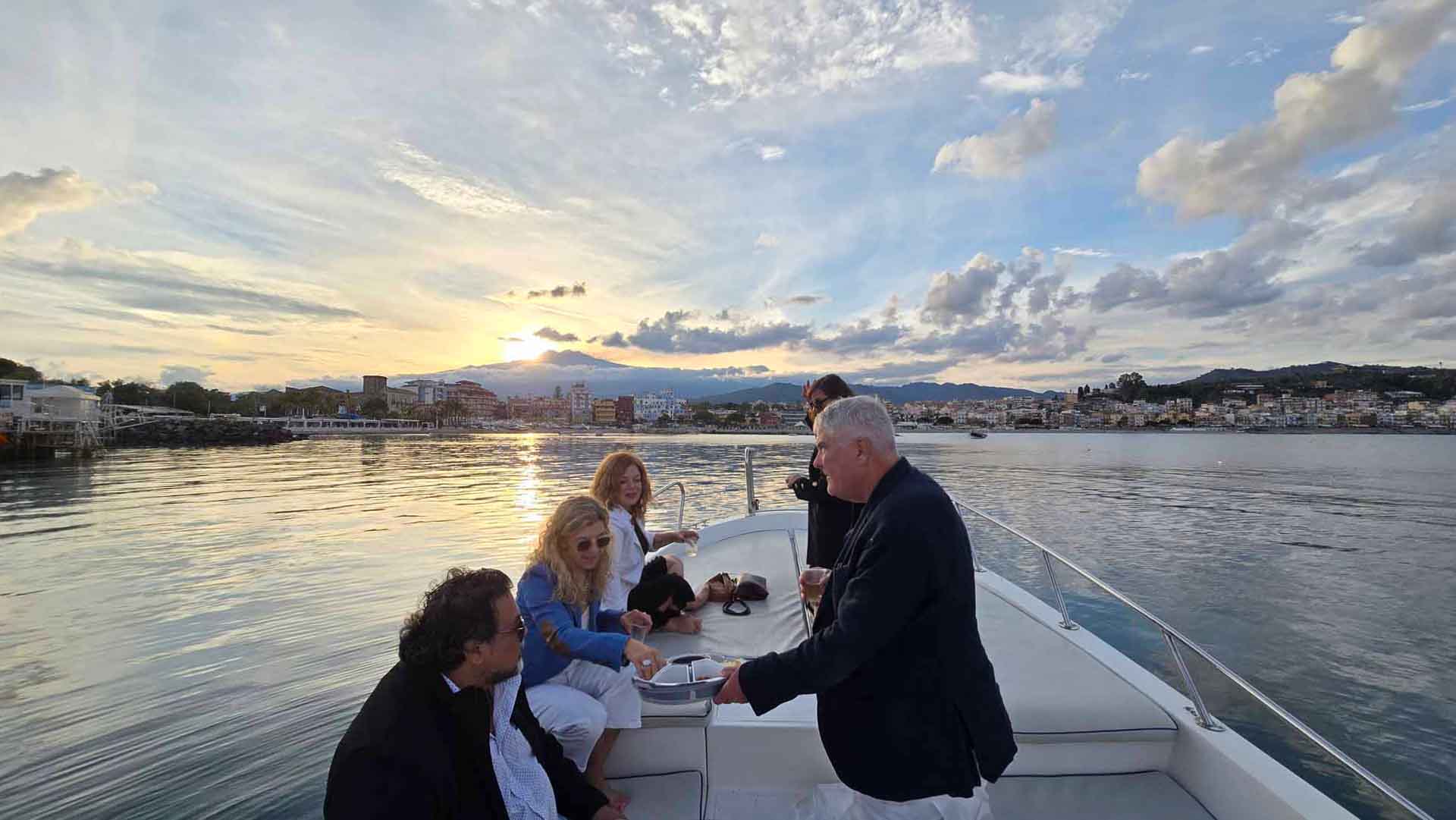 Gruppo che si gode il tramonto a bordo del tour in barca a Taormina