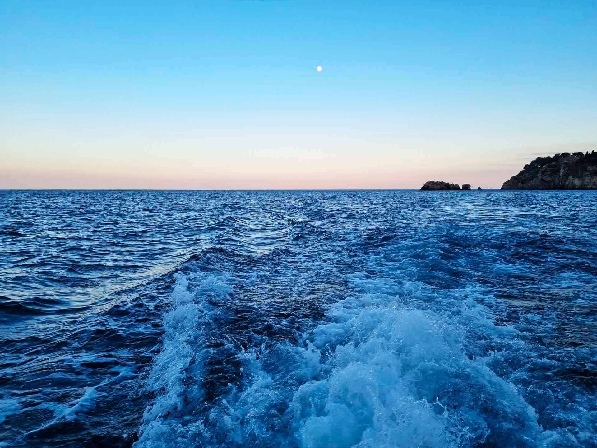 Boat anchored in a hidden bay during a Taormina sunset cruise